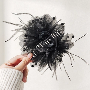 Detail of a black ostrich feather hair claw clip with mesh ruffles and black beads decor