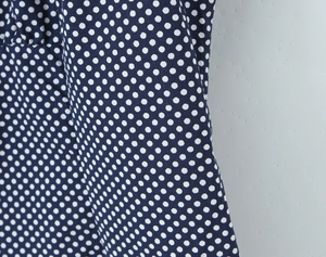 Detailed macro shot of navy blue fabric with white polka dots and soft cotton texture