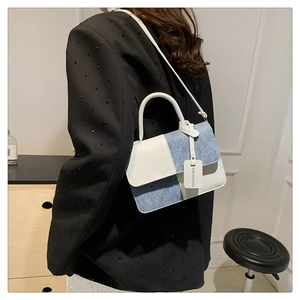 Detail of color-block flap bag in white leather and blue denim with a top handle