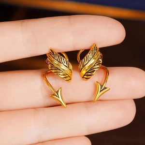 Makro-Detail des goldenen Pfeil-Ohrclips mit Flügeldesign im Vintage-Gothic-Stil