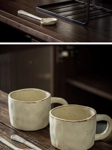 Detailed view of handmade ceramic mugs with spoons on a black metal storage rack