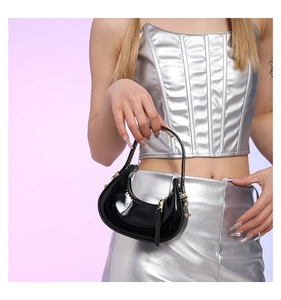 Close-up of black patent leather crescent handbag with sleek metal zipper detail