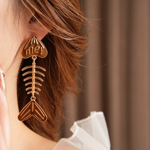 Detailaufnahme der goldenen Fischgräten-Ohrringe mit 'me!'-Gravur an einem Model getragen