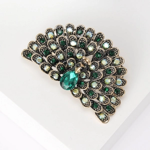 Detailed view of a vintage peacock brooch with green crystals on a bronze metal base