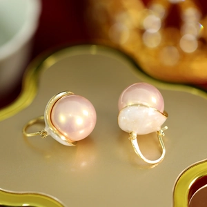 Close-up of elegant pink pearl drop earrings featuring polished golden tassels and hooks