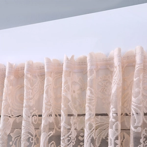 Close-up of beige lace dust cover featuring detailed floral embroidery and scalloped edges