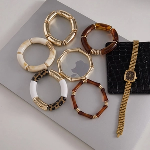 Detail of bamboo resin bracelets and gold square watch set on a modern laptop