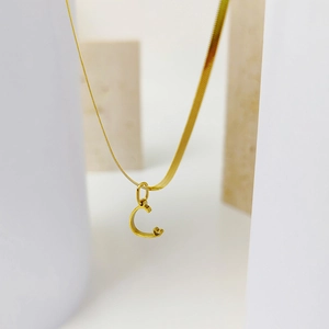 Detail of gold letter C pendant with heart accent on a sleek snake chain necklace