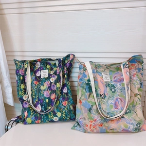 Detail of floral canvas tote bags with reinforced handles and vintage labels