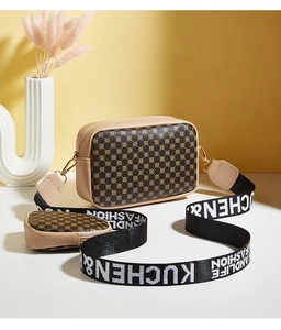 Detail of brown monogram camera bag with small coin purse and lettered webbing strap