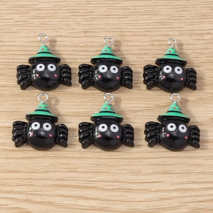 Detailed close-up of six cartoon black spider charms with green witch hats on wood background
