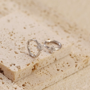 Macro shot of silver S925 huggie earrings with four-leaf clover zircon inlay