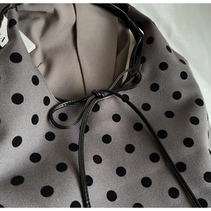 Detail of grey knitted tote bag featuring black polka dots and a decorative bow tie