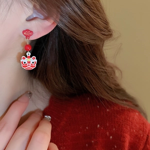 Detailed close-up of festive red lion dance earrings with Rich lettering and lucky pattern