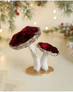 Macro view of burgundy velvet mushrooms with gold glitter on decorative base