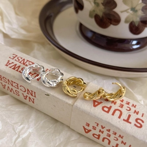 Detailed close-up of twisted rope texture earrings in gold and silver finishes