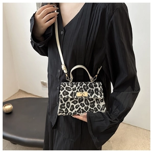 Model showcasing a leopard print crossbody bag with white handle and gold metal clasp