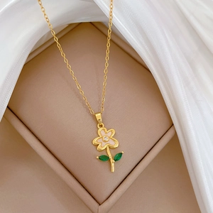 Close-up of gold flower necklace with pink enamel petals and green zircon leaves on silk