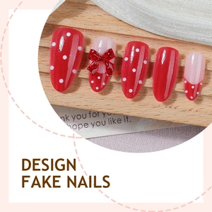 Red almond press-on nails with white polka dots and 3D bow accent on wood background