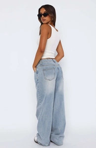 Detail view of the back pockets and relaxed silhouette of light blue wide-leg jeans
