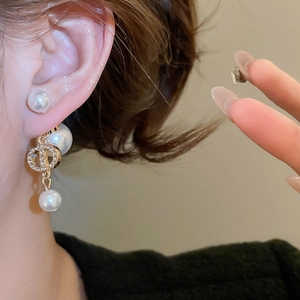 Close-up of gold plated pearl earrings with zircon inlay on a model's ear