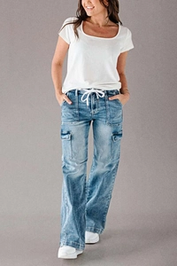 Detail of blue denim cargo pants showing the drawstring waist and multiple utility pockets