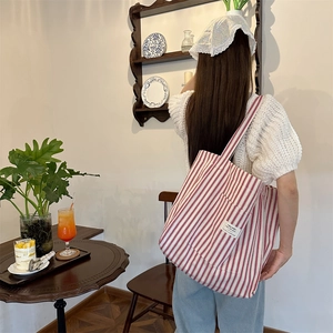 Detail of red and white striped canvas tote bag showing the exterior pocket with text