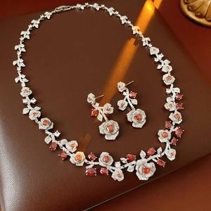 Macro detail of silver necklace and earrings with red flower jewels and clear stones