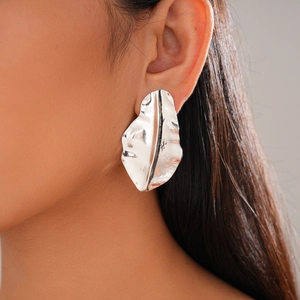 Close-up of silver irregular leaf earring with crumpled texture on woman's ear