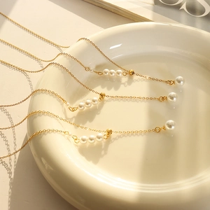Elegant French vintage gold chain necklace featuring white round pearls on white ceramic