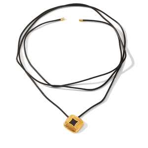 Macro detail of gold square pendant with black gemstone on multi-strand cord necklace
