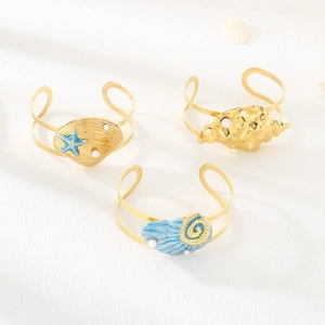 Detailed close-up of gold ocean theme bangles with shells, starfish and pearls