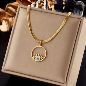 Detailed view of gold evil eye pendant with blue eye element on flat snake bone chain