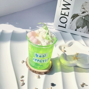 Detailed view of mint green jelly dessert candle with cream and pink hearts on a tray