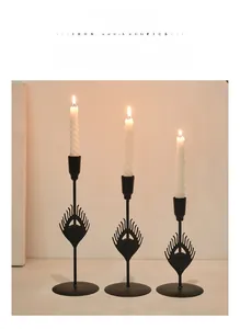 Macro shot of matte black iron candlesticks with decorative peacock feather cutouts