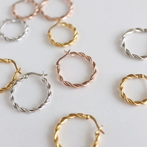 Close-up of twisted sterling silver hoop earrings in gold, silver, and rose gold finishes