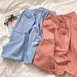 Detail of durable cotton half-aprons in blue and pink with side pockets and waist pleats