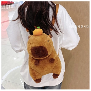 Cute brown capybara plush backpack with orange decoration shown worn on a person's back