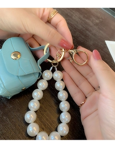 Close-up of light blue crocodile texture mini pouch with large pearl strap and gold hardware