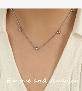 Close-up of minimalist silver heart pendant necklace on model with white ribbed top
