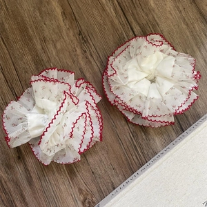 Chouchous en dentelle fleurie avec bordure contrastée rouge sur fond de bois