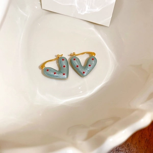 Close-up of vintage heart hoop earrings with blue enamel, red polka dots and gold finish