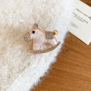 Macro shot of pink enamel rocking horse brooch with gold plating and sparkling zircons