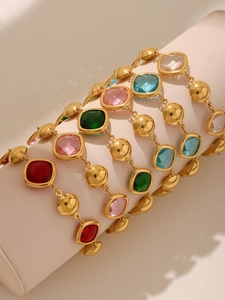 Close-up of gold-plated bracelets featuring colorful Czech glass stones on a velvet display