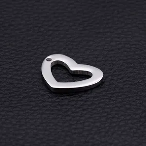 Polished heart-shaped hollow stainless steel pendant on a textured black background