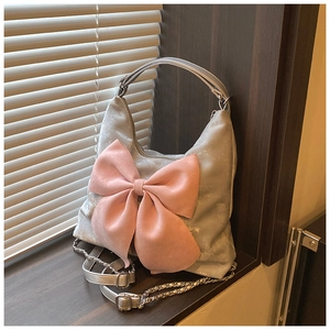 Detail of silver handbag with a large pink bow, metallic texture, and silver chain strap