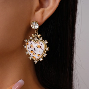 Retro heart leopard print earrings with rhinestones and bow accent worn by model