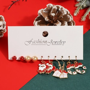 Detail of Christmas earring set featuring Santa, gift box, and wreath on display card