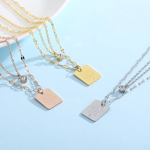 Detail of layered stainless steel chains with engraved square pendant and crystal charm