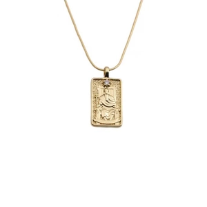 Macro view of gold plated necklace featuring a rectangular embossed pendant with a small gem